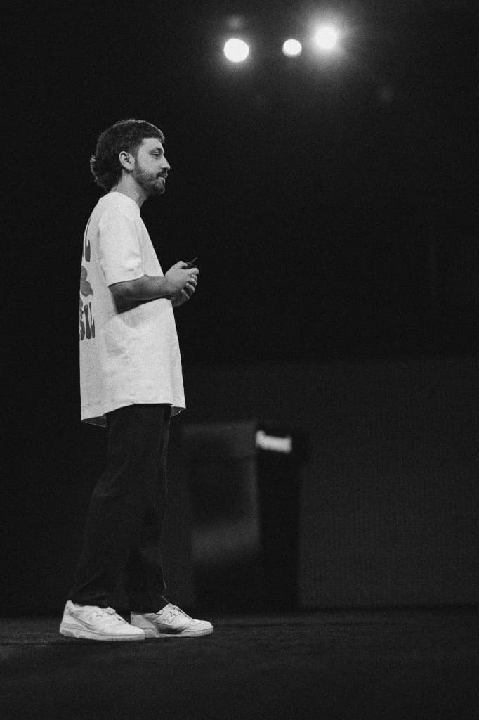 A speaker in a white T-shirt standing on stage