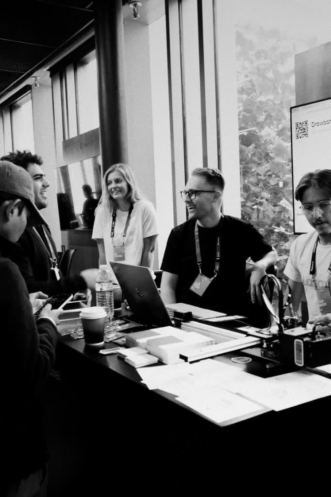 Attendees gathered around a drawbot by the windows